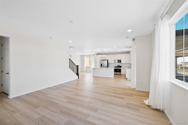 unfurnished living room featuring stairs, light wood-style flooring, recessed lighting, and baseboards