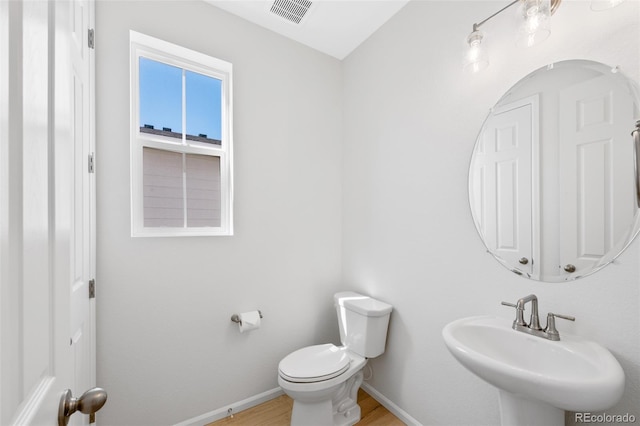 bathroom with a sink, baseboards, toilet, and wood finished floors
