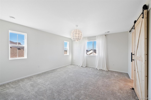 unfurnished bedroom with a barn door, light carpet, baseboards, and a chandelier