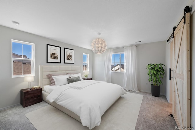 bedroom with a barn door, light carpet, and baseboards