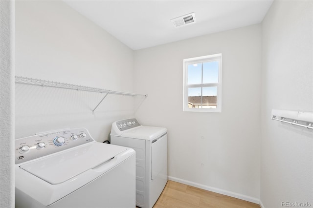 washroom featuring washer and dryer, light wood-style flooring, and baseboards