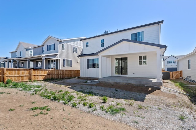rear view of house with board and batten siding, fence, and a patio area