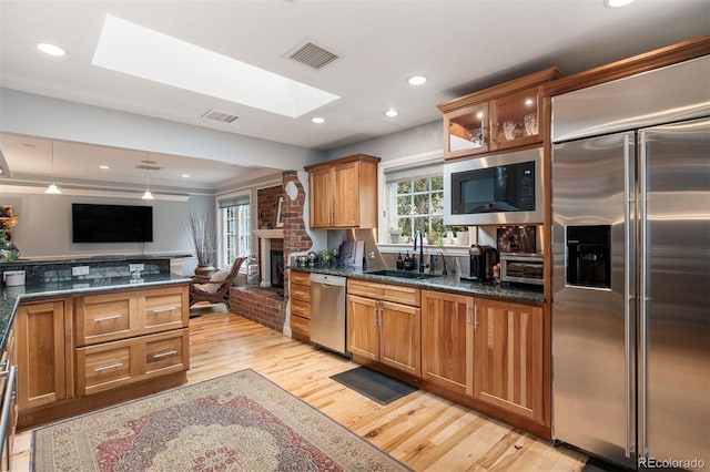 4011 S Ivy Ln, Cherry Hills Village, CO 80111 - kitchen with built in appliances, a skylight, a brick fireplace, light wood-type flooring, and brown cabinets