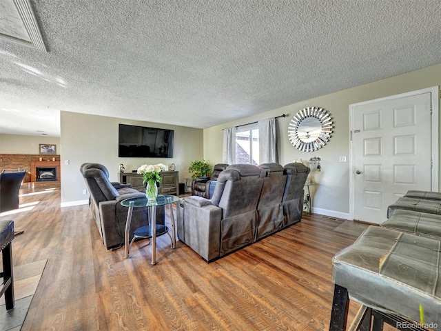 living area with a textured ceiling, baseboards, wood finished floors, and visible vents