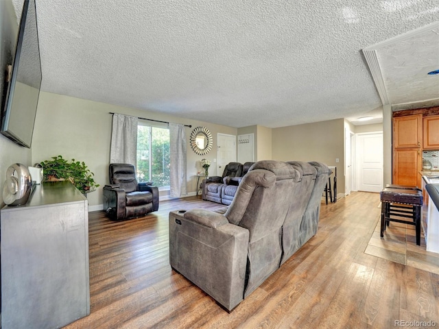 living area with baseboards, light wood-type flooring, and a textured ceiling