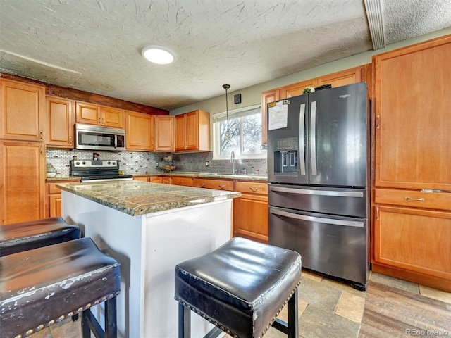 kitchen with a kitchen island, tasteful backsplash, a sink, a breakfast bar, and stainless steel appliances