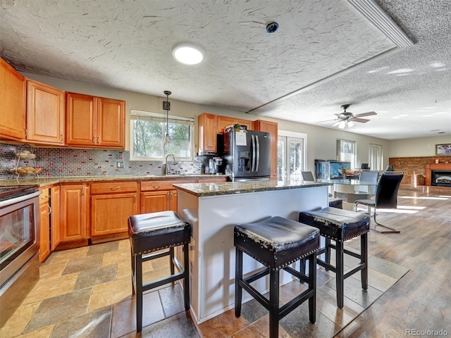 kitchen with electric range, black fridge, a sink, a breakfast bar area, and tasteful backsplash