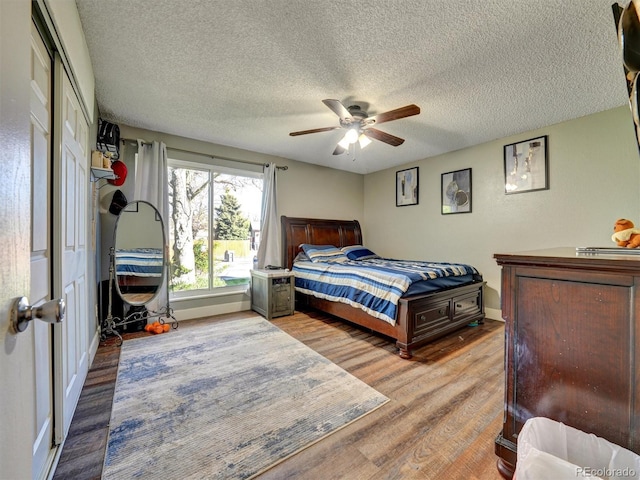 bedroom featuring baseboards, a textured ceiling, ceiling fan, and wood finished floors