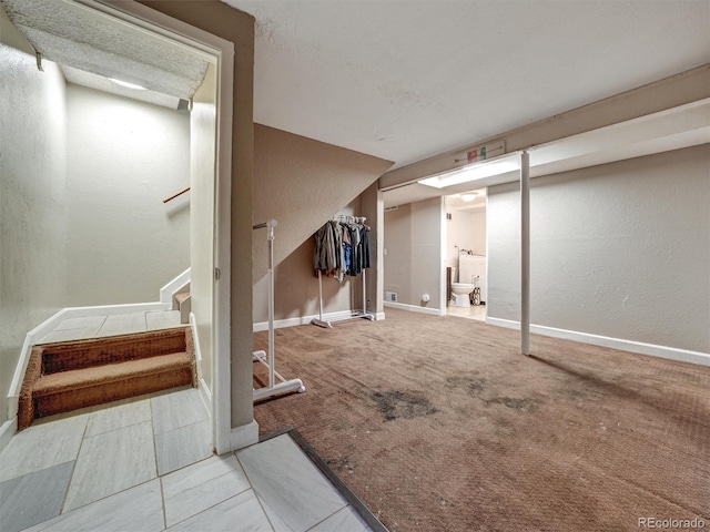 finished basement featuring stairway, baseboards, and a textured wall