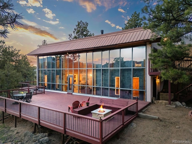 8791 Grizzly Way, Evergreen, CO 80439 - rear view of house featuring a fire pit, a wooden deck, and a sunroom