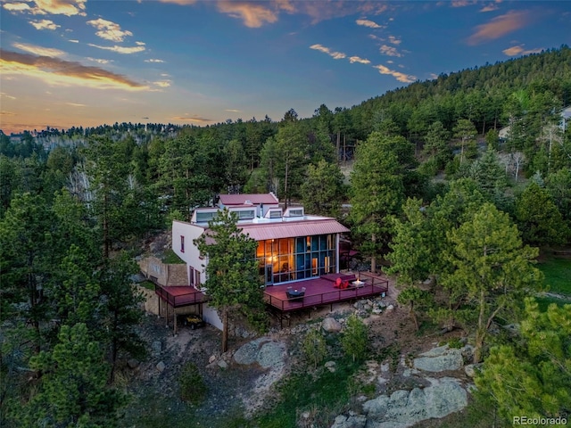 8791 Grizzly Way, Evergreen, CO 80439 - back of property at dusk with a forest view, a deck, and metal roof