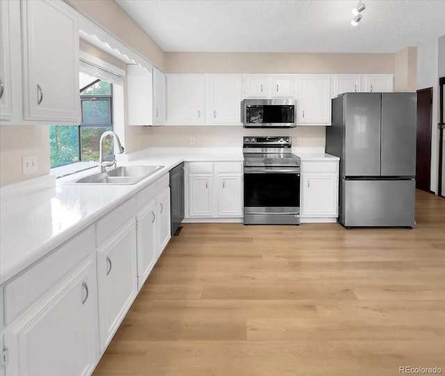 kitchen featuring light countertops, white cabinetry, appliances with stainless steel finishes, and light wood finished floors