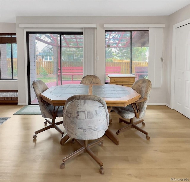 dining area with baseboards, light wood-style flooring, and a wealth of natural light