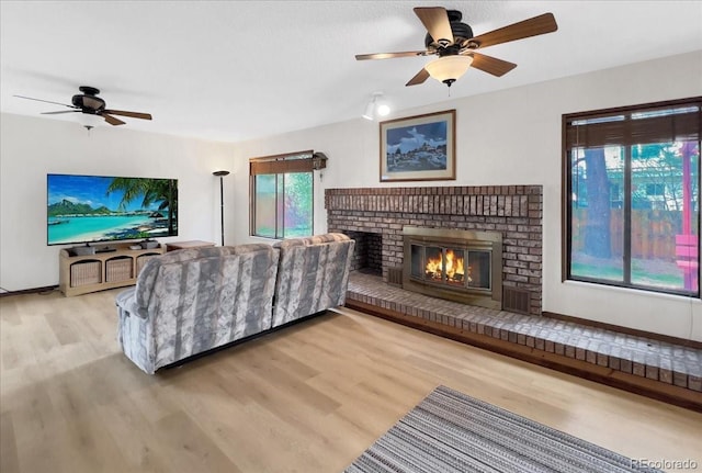living room with baseboards, ceiling fan, wood finished floors, and a fireplace