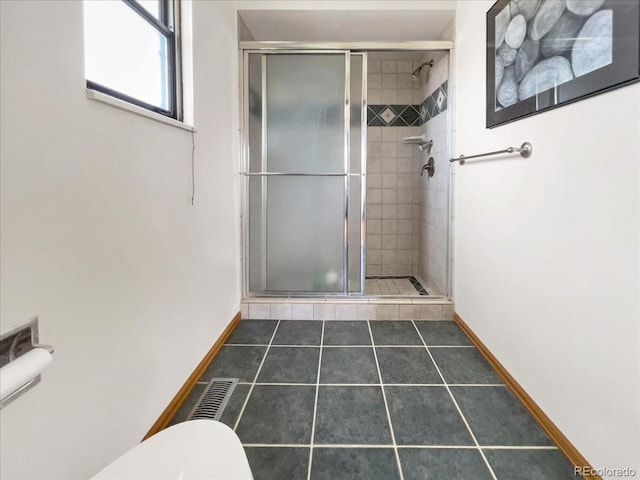 bathroom featuring baseboards, tile patterned flooring, a shower stall, and toilet