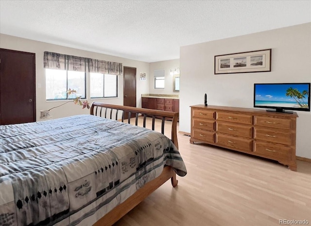 bedroom with a textured ceiling and light wood finished floors