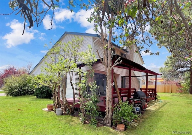 view of home's exterior featuring a lawn, fence, and a wooden deck