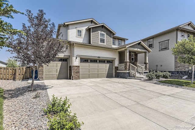 view of front facade featuring stone siding, driveway, an attached garage, and fence