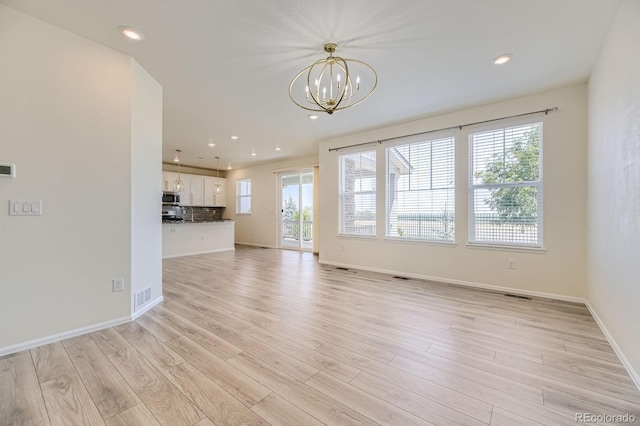 unfurnished living room with light wood-type flooring, visible vents, a chandelier, and recessed lighting