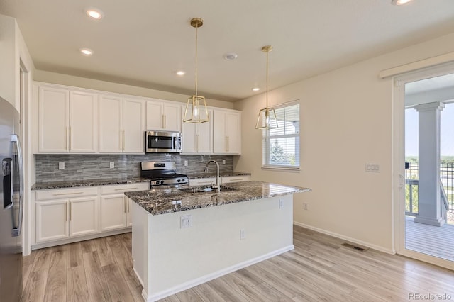 kitchen with a sink, white cabinets, backsplash, and stainless steel appliances