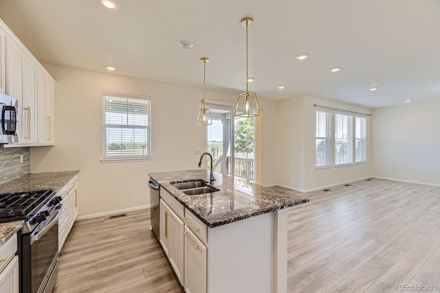 kitchen featuring light wood finished floors, appliances with stainless steel finishes, a wealth of natural light, and a sink