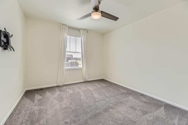 unfurnished room with carpet flooring, visible vents, baseboards, and ceiling fan