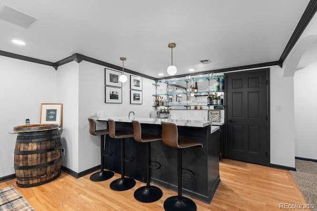 5955 Blue Sage Way, Littleton, CO 80123 - indoor wet bar featuring crown molding, light wood-style floors, hanging light fixtures, and recessed lighting