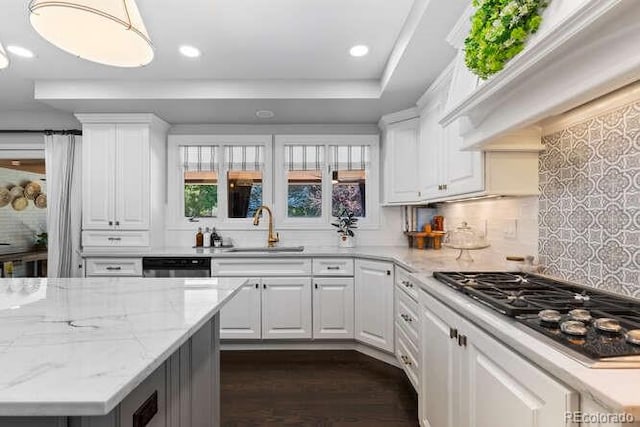 5955 Blue Sage Way, Littleton, CO 80123 - kitchen with premium range hood, stainless steel gas cooktop, tasteful backsplash, white cabinets, and dark wood-style floors
