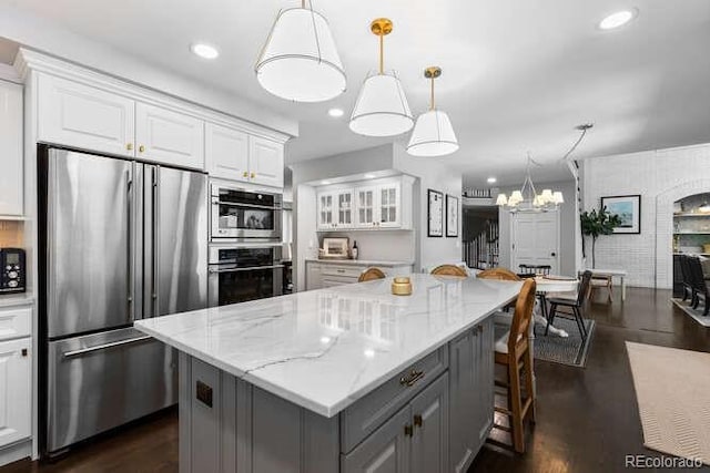 5955 Blue Sage Way, Littleton, CO 80123 - kitchen with appliances with stainless steel finishes, gray cabinets, white cabinetry, a kitchen breakfast bar, and dark wood-type flooring