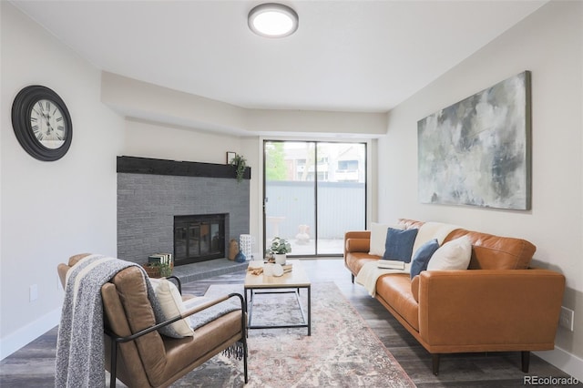 living room with dark hardwood / wood-style flooring and a brick fireplace