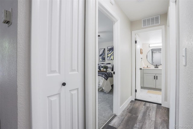 hall featuring sink and dark carpet