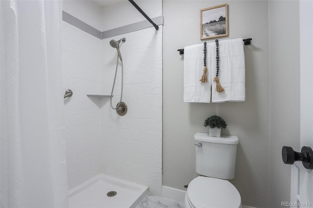 bathroom with a tile shower and toilet