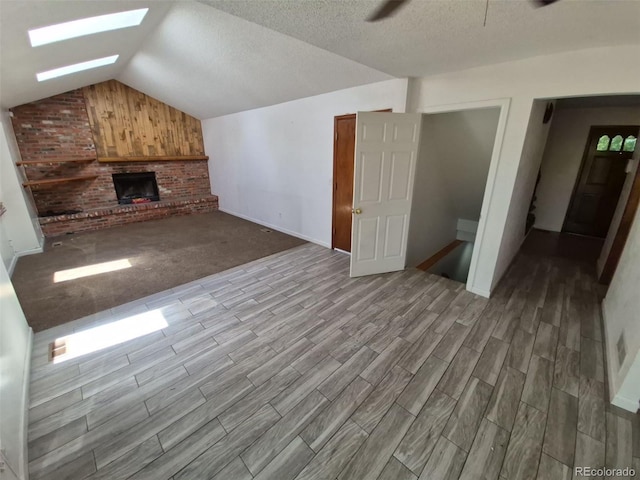 3136 S Cathay Cir, Aurora, CO 80013 - unfurnished living room featuring a skylight, lofted ceiling, ceiling fan, a fireplace, and wood finished floors