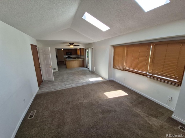 3136 S Cathay Cir, Aurora, CO 80013 - unfurnished living room with carpet flooring, vaulted ceiling, a skylight, a textured ceiling, and baseboards