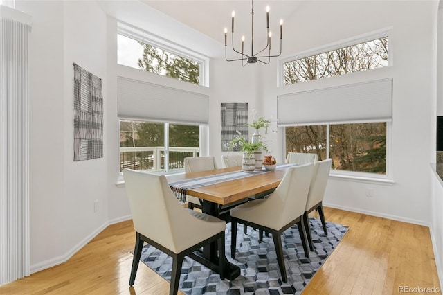 dining room featuring a towering ceiling, light hardwood / wood-style flooring, and a notable chandelier