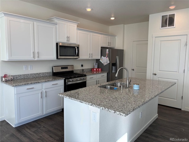 kitchen featuring sink, white cabinetry, light stone counters, appliances with stainless steel finishes, and an island with sink