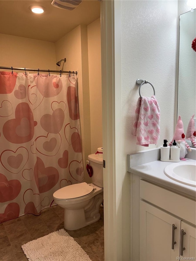 bathroom with vanity, tile patterned flooring, toilet, and walk in shower