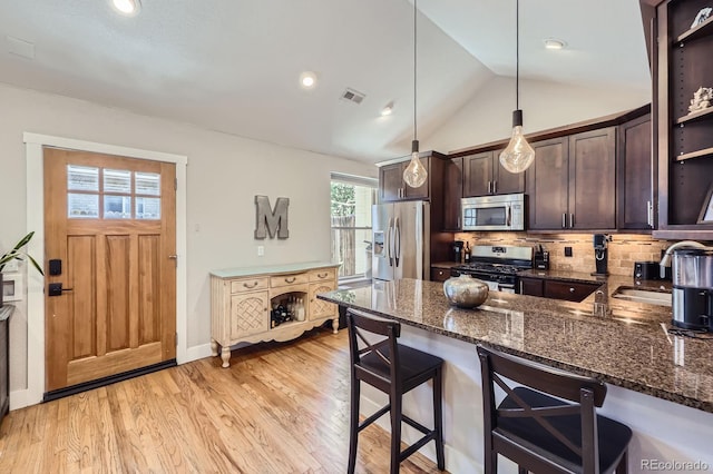 2841 N Columbine St, Denver, CO 80205 - kitchen with stainless steel appliances, dark brown cabinets, a breakfast bar area, dark stone countertops, and decorative backsplash