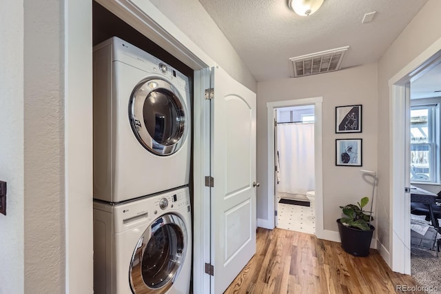 2841 N Columbine St, Denver, CO 80205 - laundry room with stacked washer and clothes dryer, wood finished floors, and a textured ceiling