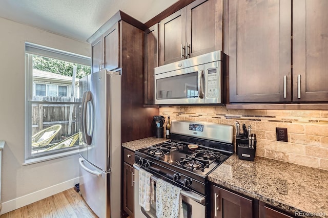 2841 N Columbine St, Denver, CO 80205 - kitchen with stainless steel appliances, backsplash, light stone counters, dark brown cabinets, and light wood-type flooring