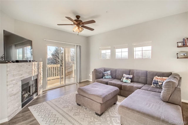 living room with a ceiling fan, a fireplace, baseboards, and wood finished floors