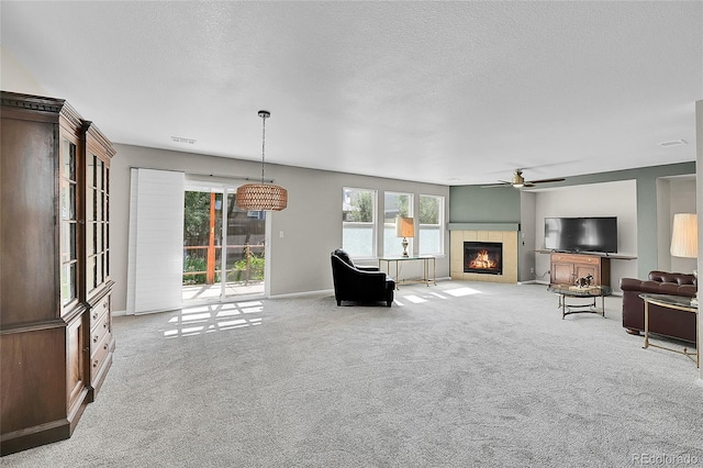 5564 Kalispell St, Denver, CO 80239 - carpeted living area with a tiled fireplace, a ceiling fan, and a textured ceiling