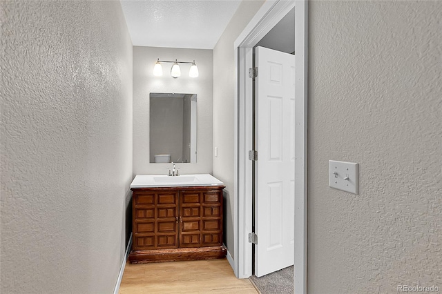 5564 Kalispell St, Denver, CO 80239 - bathroom with a textured wall, vanity, and wood finished floors