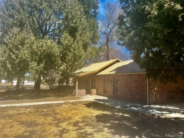 300 3rd St, Saguache, CO 81149 - ranch-style house featuring brick siding, metal roof, and a patio area