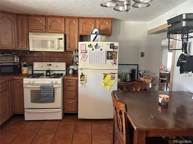 300 3rd St, Saguache, CO 81149 - kitchen with decorative backsplash, a textured ceiling, brown cabinets, dark tile patterned flooring, and white appliances