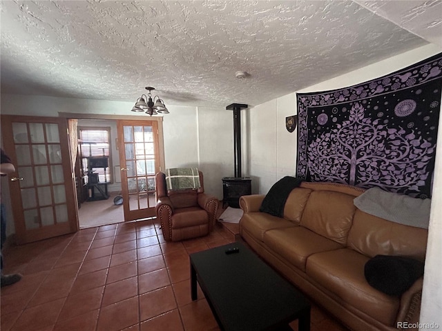 300 3rd St, Saguache, CO 81149 - living room featuring french doors, a textured ceiling, tile patterned flooring, a wood stove, and a notable chandelier