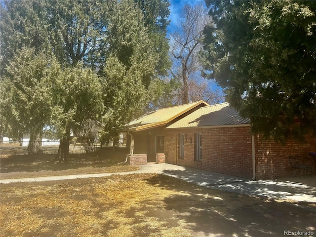 300 3rd St, Saguache, CO 81149 - ranch-style house featuring brick siding, metal roof, and a patio area