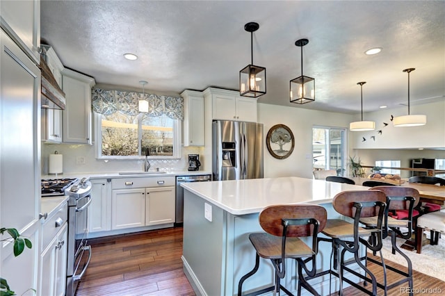 13915 W 73rd Ave, Arvada, CO 80005 - kitchen featuring stainless steel appliances, light countertops, recessed lighting, a breakfast bar, and healthy amount of natural light