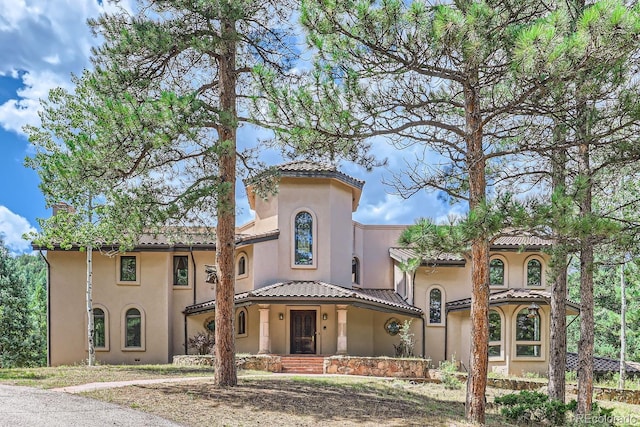 mediterranean / spanish home with stucco siding, a tiled roof, and a chimney