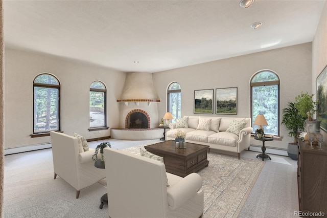 living room with a wealth of natural light, baseboard heating, and light carpet